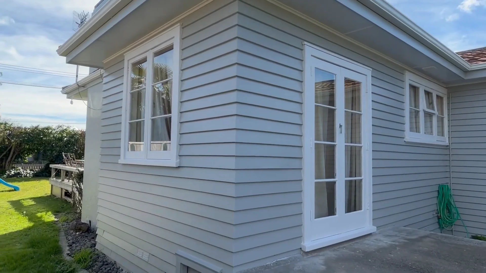 Grey weatherboards, white window trim and a glazed door after the Hamilton exterior restoration